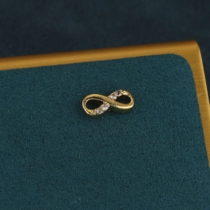 Macro d'une boucle d'oreille infini en or sertie de zircons sur une surface sombre