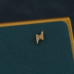 Gros plan d'un clou d'oreille éclair doré serti de zircons sur velours vert foncé