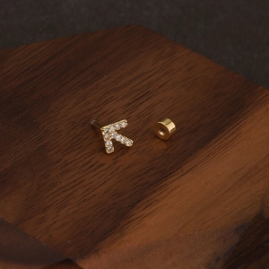 Detailed macro view of gold-plated K letter stud earring with sparkling crystal pavé
