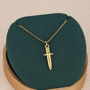 Golden stainless steel dagger pendant necklace with box chain on green velvet