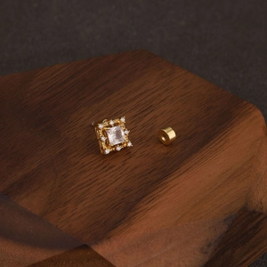 Macro view of gold square zirconia stud earrings with halo setting on wood stand