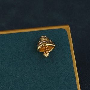 Close-up of golden mushroom helix piercing stud with sparkling zircon crystal inlay