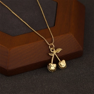 Golden cherry pendant necklace with fluid texture on an elegant wooden jewelry stand