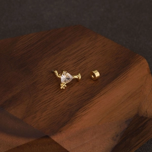 Macro view of a gold flower cartilage earring with a triangular zircon and screw back