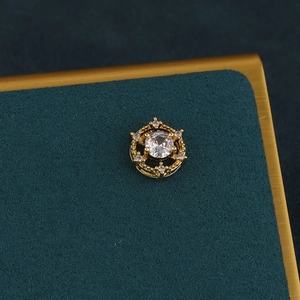 Macro shot of gold floral cartilage earring with a central diamond and crown details