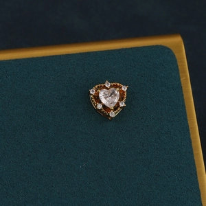 Macro view of gold heart piercing stud with a clear zircon and prong-set small stones