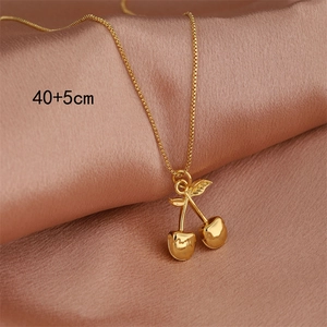 Golden cherry pendant necklace in 18k stainless steel on pink silk background