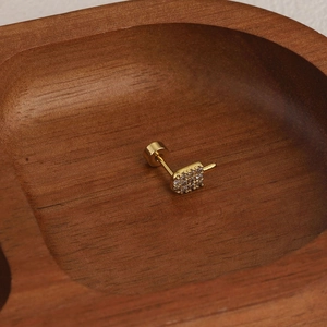 Détail macro d'une boucle d'oreille en forme de doigt d'honneur doré sertie de zircons