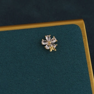 Detail of flower cartilage earring with pear-cut clear zircons and gold bow accent