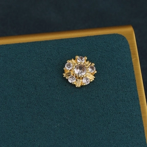 Macro view of gold flower cartilage stud with sparkling cubic zirconia on green velvet