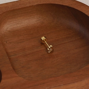 Vue détaillée du piercing couronne dorée avec cristaux sur fond de texture en bois