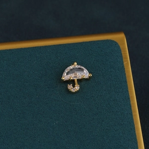 Close-up of a gold umbrella-shaped earring with faceted zircon and small diamonds