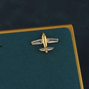 Detailed macro view of a gold airplane cartilage stud earring with cubic zirconia stones