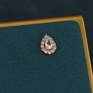 Macro detail of gold flower teardrop cartilage piercing with clear crystal halo