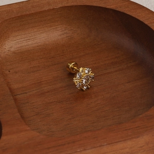 Macro shot of gold-plated floral helix stud with sparkling cubic zirconia on wood