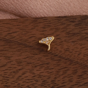 Détail de boucles d'oreilles dorées en forme d'éventail avec zircons sur bois et tissu