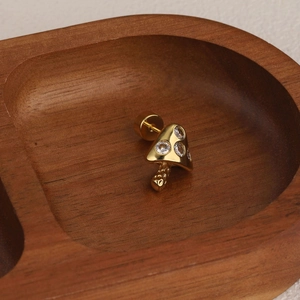 Detailed view of mushroom stud earring in gold with three white cubic zirconia stones