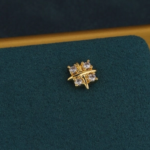 Macro shot of a gold-plated star cartilage piercing with four sparkling zircon stones