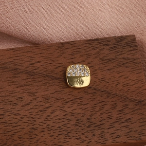 Détail d'une boucle d'oreille dorée sertie de zircons sur un fond en satin soyeux