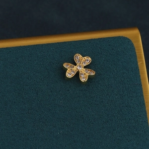 Macro detail of gold clover cartilage earring with shimmering pavé crystal petals