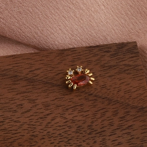 Gros plan sur boucle d'oreille crabe dorée avec pierre rouge et diamants sur soie