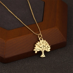 Polished 18K gold tree of life pendant on a box chain displayed on a wooden stand