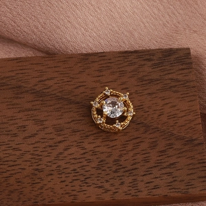 Macro shot of gold floral cartilage piercing stud with round zircon on walnut wood surface
