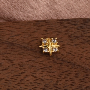 Detailed close-up of golden square starburst earring with zircon stones on silk