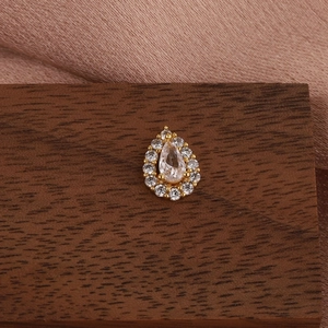 Close-up of a gold teardrop earring with cubic zirconia on a rustic wooden display