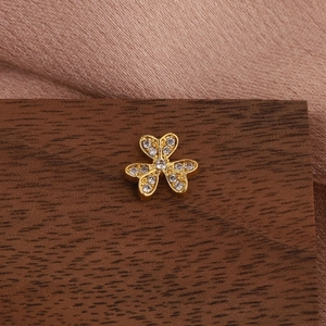 Macro shot of gold three-petal flower earring with inlaid cubic zirconia on wood surface