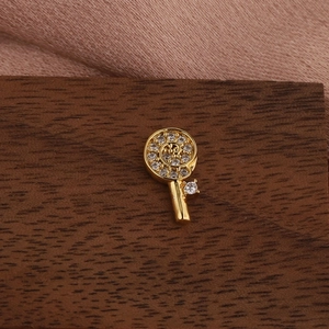 Macro shot of a gold lollipop-shaped earring with spiral crystal settings on dark wood