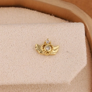 Macro shot of 18K gold star stud earring with wings and sparkling zircon stone