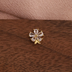 Macro shot of gold flower cartilage earring with pear-cut crystals and bow detail