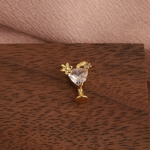 Macro detail of cocktail glass stud earring with heart zircon and golden flower