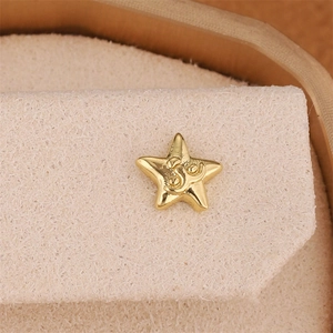 Star-shaped 18K gold plated earring with engraved Om symbol on velvet cushion