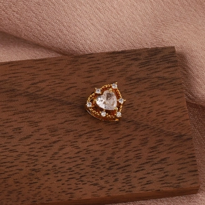 Detail view of heart-shaped earring with clear stone and small diamonds on gold setting