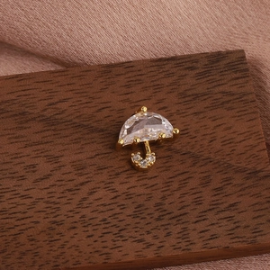 Detailed close-up of a golden umbrella-shaped earring with clear cubic zirconia on wood