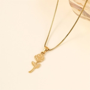 Collier élégant pendentif rose dorée avec chaîne boîte sur un fond crème minimaliste