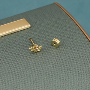 Macro shot of gold-plated star earring with white zircon inlay on a leather surface