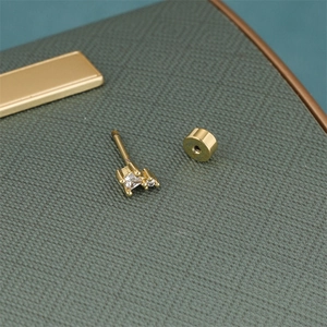 Macro detail of gold-plated pentagram ear stud with square and round zircon stones