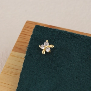Macro shot of 18K gold star earrings featuring cubic zirconia inlays on green felt