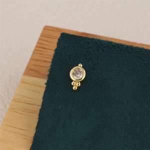 Macro shot of 18K gold plated star zircon stud earring with polished beads on leather