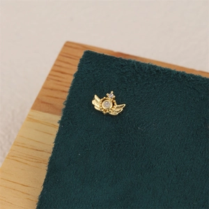 Detail of 18K gold plated winged star earring with zircon inlay on green velvet
