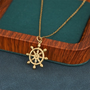 Polished 18K gold nautical ship wheel pendant necklace on green velvet box