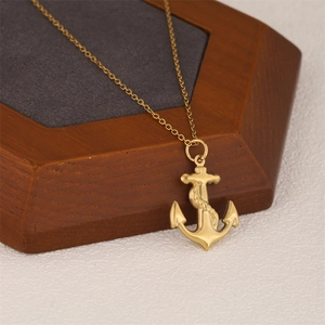 Golden anchor pendant necklace with rope texture on a hexagonal wooden display stand