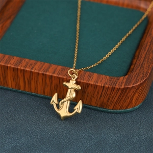 Elegant gold anchor pendant necklace with rope detail on vintage wood and green texture background