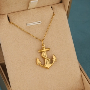 Golden anchor pendant necklace with rope texture displayed in a beige velvet gift box