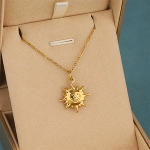 Collier pendentif soleil doré poli avec rayons creux sur boîte à bijoux en velours