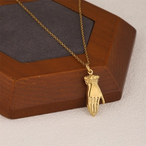 Vintage gold hand pendant necklace with victorian palm charm on a wooden display