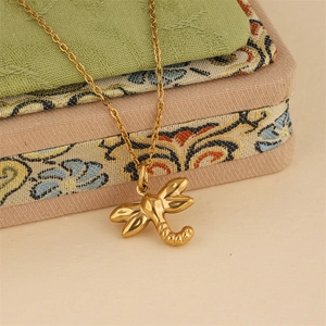 Elegant gold stainless steel dragonfly necklace with textured wings on vintage fabric